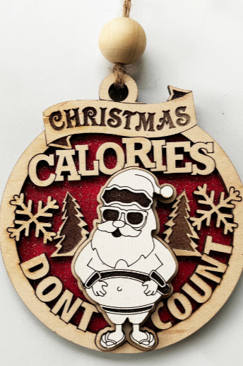 Wooden Christmas ornament with Santa and text "Christmas Calories Don't Count" in a playful design.